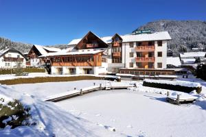un grande edificio nella neve di fronte di Hotel Naggler Weissbriach a Weissbriach