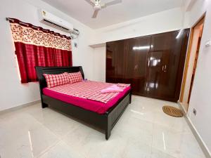 a small bed in a room with a red curtain at TrueLife Homestays - Alamelu Avenue - Fully Furnished AC 2BHK Apartments in Tirupati - Walkable to Restaurants & Super Market - Fast WiFi - Kitchen - Easy access to Airport, Railway Station, Sri Padmavathi & Tirumala Temple in Tirupati