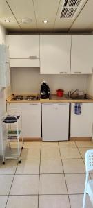 a kitchen with white cabinets and a table and a chair at MENTON BORD DE MER Studio calme avec balcon, Ascenseur, Climatisation, Ideal location quiet near sea, balcony, elevator, AC in Menton