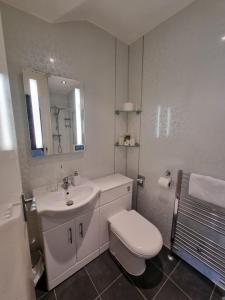 a white bathroom with a toilet and a sink at The Fawley Guest house in Shanklin