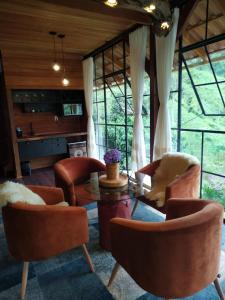 a living room with chairs and a table and windows at Casa do Lago Caparaó in Pedra Menina