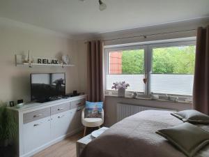 a bedroom with a bed and a tv and a window at Appartement Relax Sankt Peter Ording in Sankt Peter-Ording