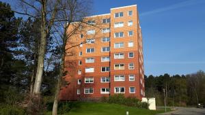 wysoki budynek z czerwonej cegły z drzewem przed nim w obiekcie Appartement Relax Sankt Peter Ording w mieście Sankt Peter-Ording