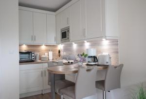 uma cozinha com armários brancos e uma mesa e cadeiras em Appartement Relax Sankt Peter Ording em Sankt Peter-Ording