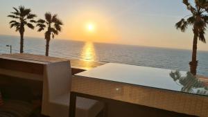 een balkon met een tafel en palmbomen en de oceaan bij טרסת העץ המלכותית חוף צאנז עם בריכת זרמים פרטית לציבור החרדי in Netanya