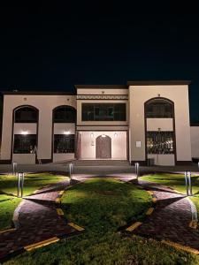 بيت العز السياحي Al-Ezz Tourist House في صحار: مبنى كبير في الليل مع انارته