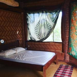 Bett in einem Zimmer mit Fenster in der Unterkunft Chalé na Chapada, com acesso ao Rio São Miguel in Sao Jorge