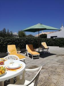 a patio with chairs and a table and an umbrella at Casa Oliveirinha - Sagres in Sagres