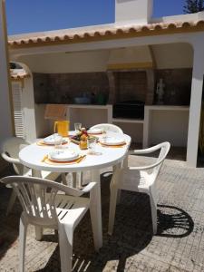 una mesa blanca y dos sillas con comida. en Casa Oliveirinha - Sagres en Sagres