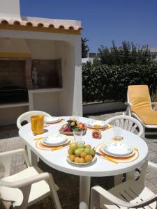 a white table with plates of fruit on it at Casa Oliveirinha - Sagres in Sagres