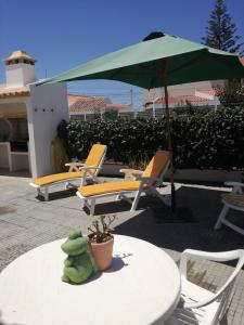 Casa Oliveirinha - Sagres في ساغريس: طاولة مع مظلة وكراسي على الفناء
