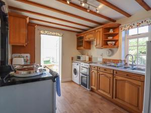 a kitchen with wooden cabinets and a sink and a dishwasher at Orchard Cottage in Ashendon
