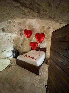 three red hearts on a bed in a stone room at La Suite Nella Roccia in Matera