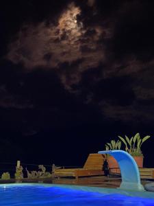 ein Schwimmbad in der Nacht mit dem Mond im Himmel in der Unterkunft Sítio com Piscina e Vista a 12km de Treze Tílias in Ibicaré
