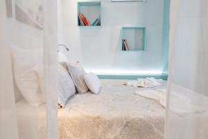 - un lit dans une chambre blanche avec des livres sur le mur dans l'établissement Theoxenia Kasos Luxury Apartments, à Panayía