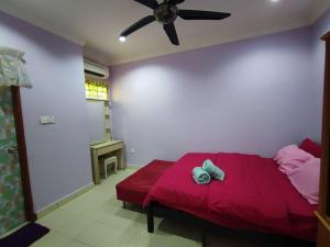 Schlafzimmer mit einem roten Bett und einem Deckenventilator in der Unterkunft Homestay D'Lily in Ipoh