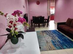 ein Wohnzimmer mit einem Sofa und einem Tisch mit Blumen in der Unterkunft Homestay D'Lily in Ipoh