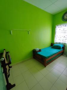 Grünes Zimmer mit einem Bett und einem Fenster in der Unterkunft Homestay D'Lily in Ipoh