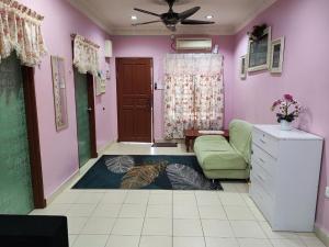 ein Wohnzimmer mit grüner Couch und rosa Wänden in der Unterkunft Homestay D'Lily in Ipoh