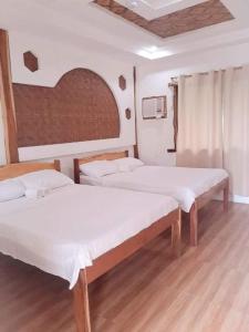 two beds in a room with wooden floors at Sand 1 Hostel in Siquijor