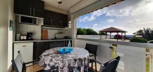una cucina con tavolo e sedie e un balcone di L'Hibiscus piscine et plage a Sainte-Luce