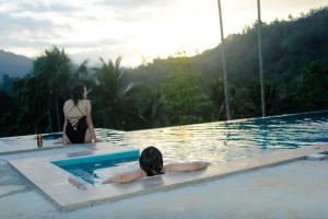 2 femmes dans une piscine d'un complexe dans l'établissement Rainforest Mount Lodge, à Deniyaya