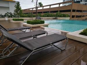 a pair of chairs sitting on a deck next to a swimming pool at Camellia Mesahill Homestay in Nilai