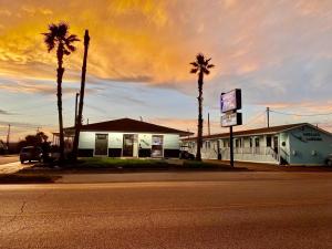 a building on the corner of a street with palm trees at Amelia's Landing in Port Aransas