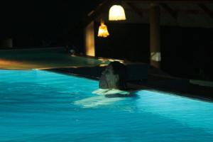 a woman laying in a swimming pool at night at Rainforest Mount Lodge in Deniyaya