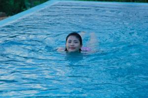 uma jovem a nadar numa piscina em Rainforest Mount Lodge em Deniyaya