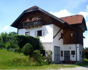 Casa blanca con techo de madera y balcón en Haus Stöllinger, en Hof bei Salzburg
