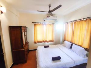 um quarto com uma cama branca e uma ventoinha de tecto em Hilltop 4 BHK Villa with Private Swimming Pool near Candolim em