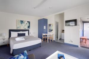 a hotel room with a bed and a table and chairs at Tin Can Bay's Sleepy Lagoon Motel in Tin Can Bay