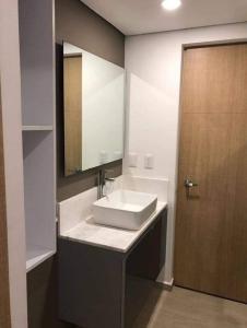 ein Badezimmer mit Waschbecken, Spiegel und Tür in der Unterkunft Estudio vacacional in Puerto Peñasco