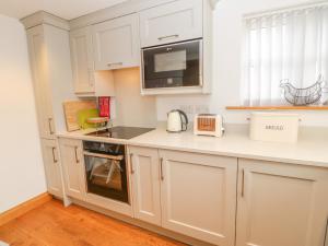 eine Küche mit weißen Schränken und einer Mikrowelle in der Unterkunft Rose Cottage in Penrith