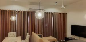 a living room with brown curtains and a television at Luxe Highway Residencies in Kottawa