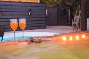 Caveirac的住宿－La yourte de Nîmes, spa , jacuzzi chalet logement insolite，两杯葡萄酒坐在游泳池旁