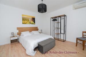 1 dormitorio blanco con 1 cama y 1 silla en LE RELAIS DES CHATEAUX, en Margaux