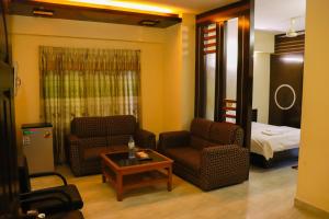 a living room with two chairs and a table and a bed at Cox Hill Tower in Cox's Bazar +20 photos