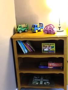 a wooden shelf with two toy trucks and books at Maison Berrichonne 2 chambres cour et jardin in Saint-Marcel