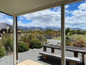 a picnic table on a porch with a view of the mountains at Mahina Cottage in Twizel