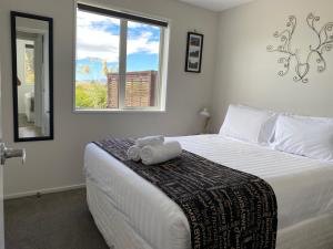 a bedroom with a large white bed with a window at Mahina Cottage in Twizel