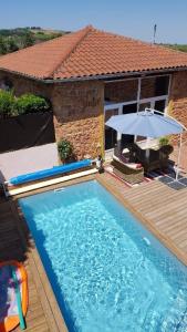 a swimming pool with an umbrella next to a house at Chambre d'hôtes Les Plaisances in Saint-Julien