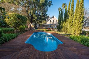 a swimming pool on a wooden deck next to a house at De Oude Pastorie in Swellendam