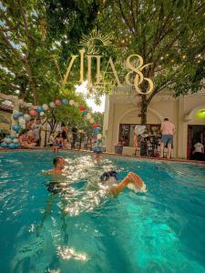 two people swimming in a swimming pool with a sign at Villa 86 in Ho Chi Minh City