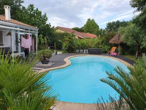 a large blue swimming pool next to a house at Chalet Cosy in Audenge