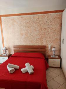 two towels on a red bed in a bedroom at Appartamento Achiazza Scala dei Turchi in Realmonte