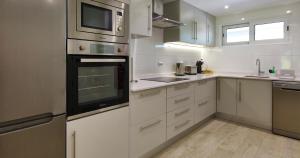 una cocina con armarios blancos y electrodomésticos de acero inoxidable en Victory Village 20B, en Quinta do Lago