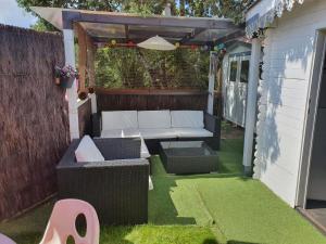a patio with a couch and a table and chairs at Chalet Cosy in Audenge