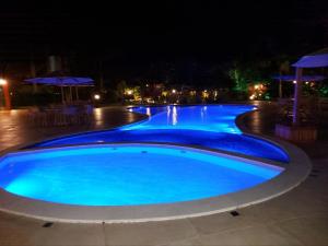 una gran piscina de agua azul por la noche en Privê Portal Baraúnas, en Gravatá